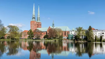 Cathedral with twin spires reflected in water.