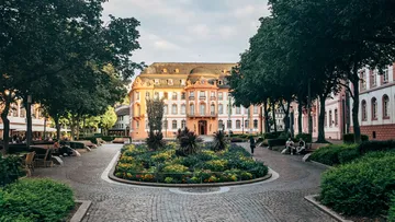 Majestic building behind lush garden and pathways.