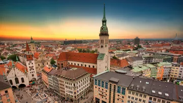 Cityscape with towers at sunset, bustling square.