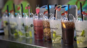 Colorful cocktails with straws on silver counter.