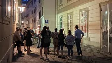 Menschen versammeln sich nachts in einer Gasse.