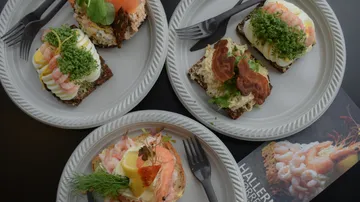Offene Sandwiches auf Tellern mit Besteck.