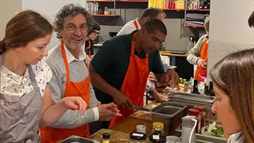 Group cooking in a kitchen, wearing aprons.