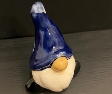 Keramikgnom mit blauem Hut auf Tisch.