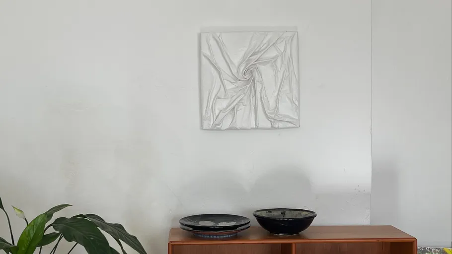 Weiße Stoffkunst an Wand über Schrank.