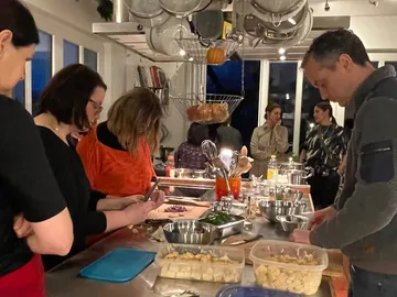 Chefs cut ingredients in a fully equipped kitchen.