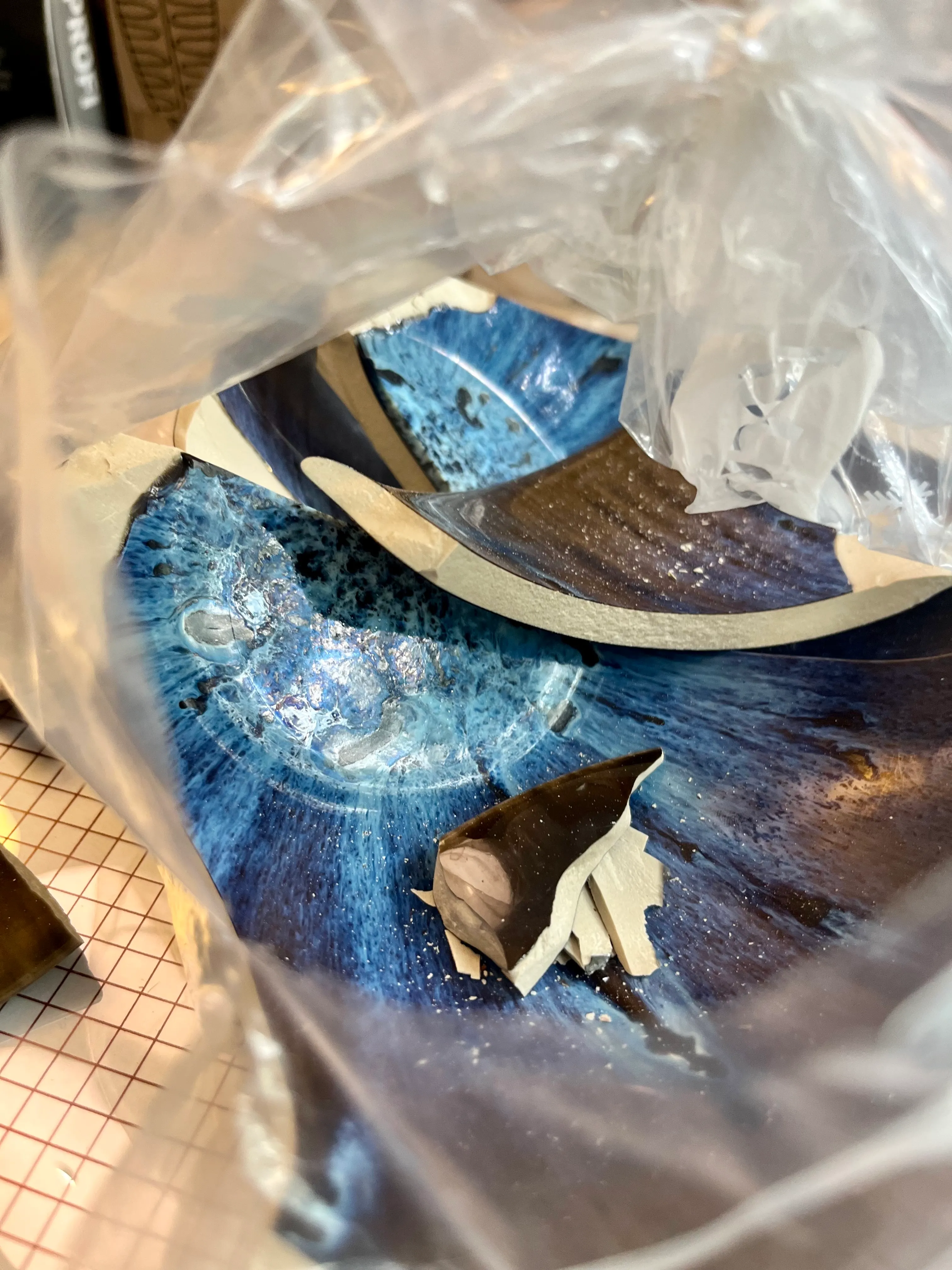 Zerbrochene blaue Keramikschale in Plastikbeutel.