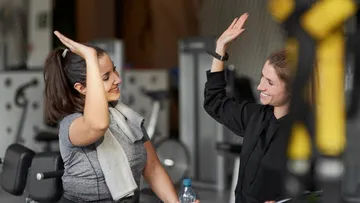 Two women high-five in a gym.