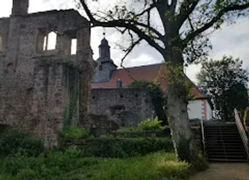 Historische Ruinen neben einer Kirche umgeben von Bäumen.