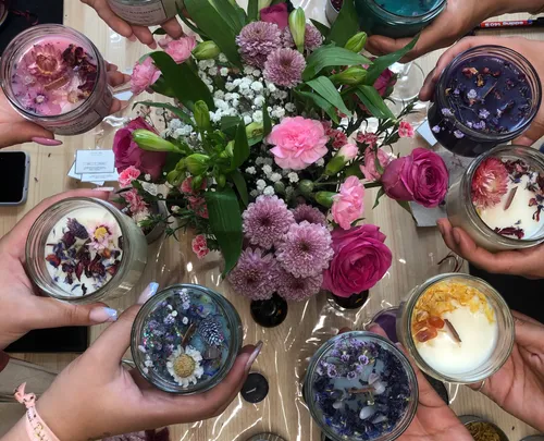 People holding candles with flowers on a table.