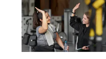 Two women high-five in a gym.