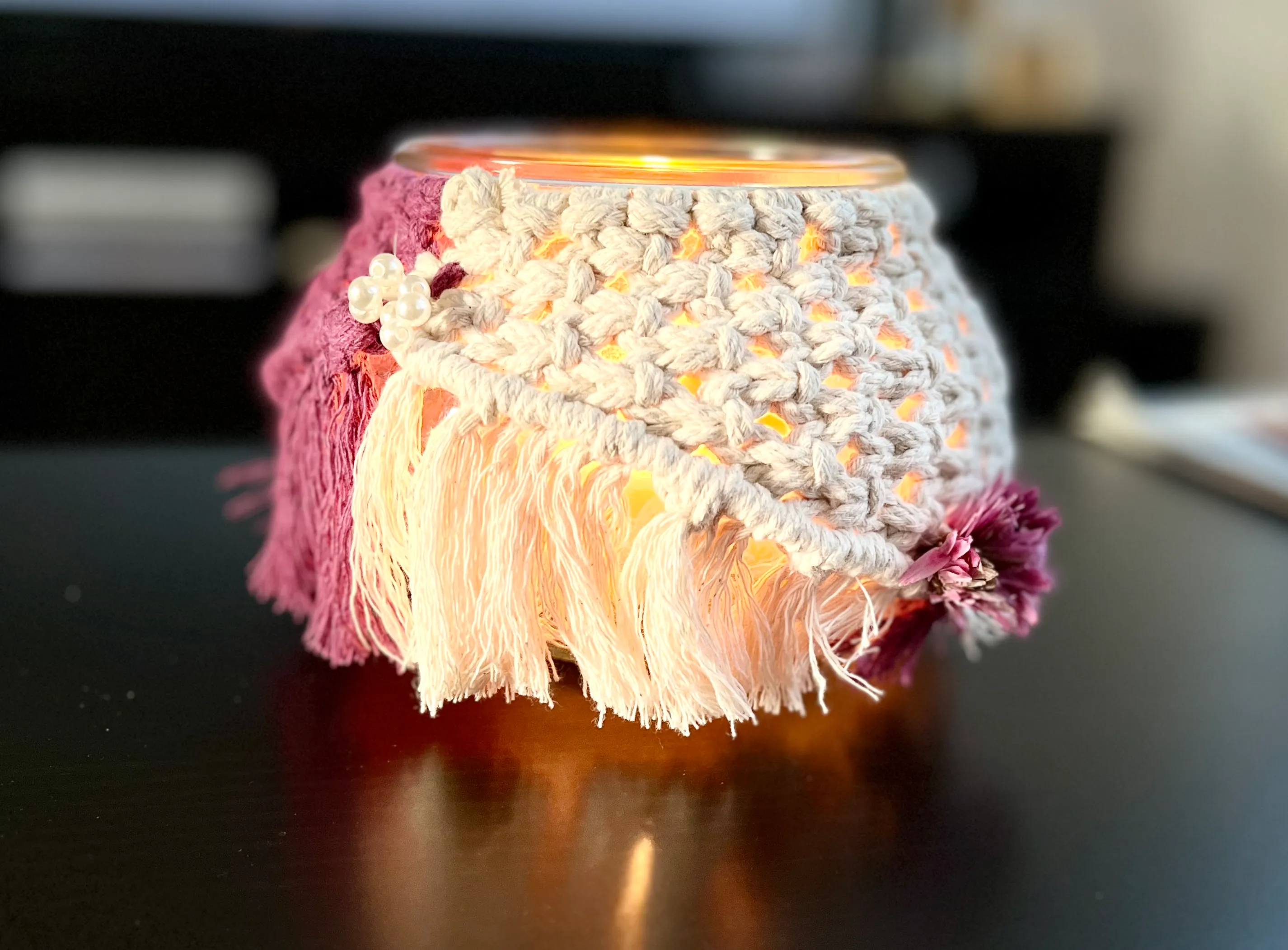 Gehäkelter Kerzenhalter mit Fransen auf Tisch.