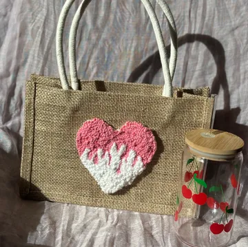 Tasche mit Herzdesign neben Kirschglas.