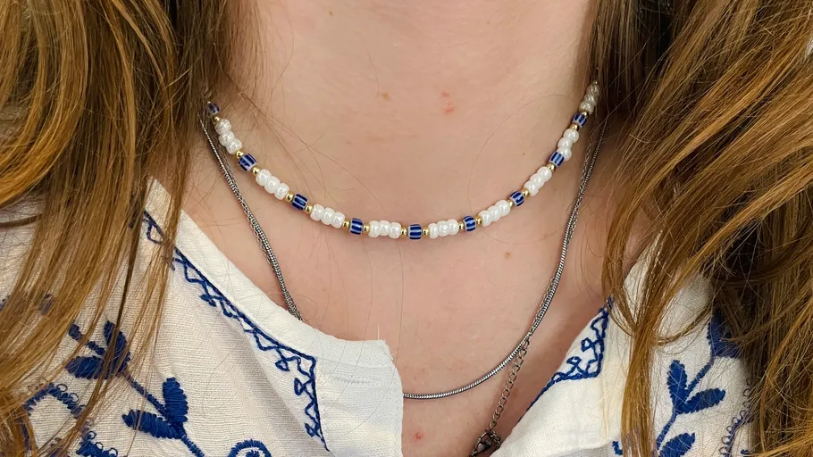 Perlenkette am Hals mit bestickter Bluse.