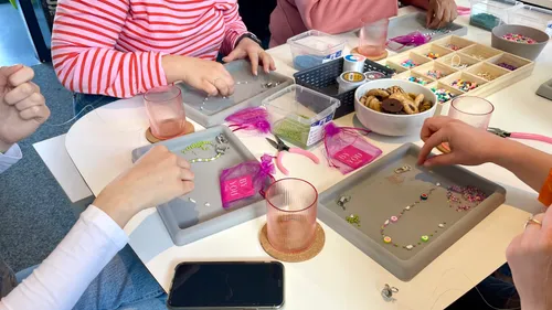 People making jewelry at a craft table.