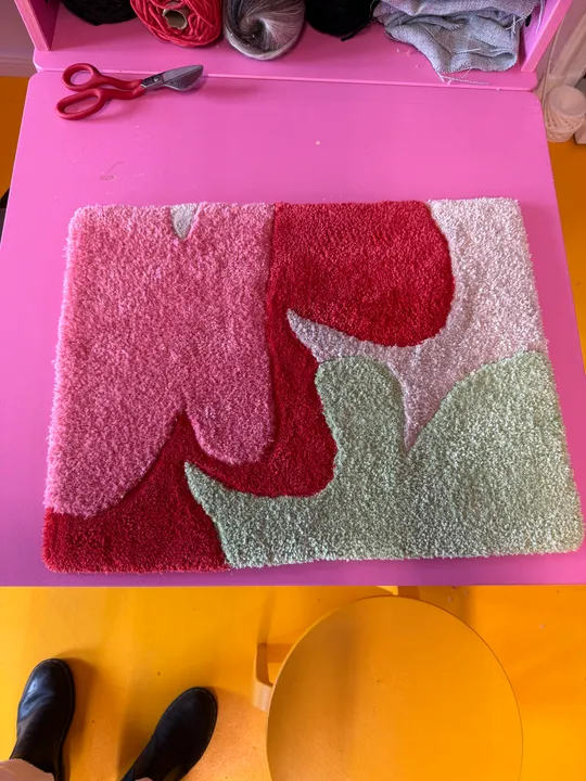 Colorful rug on pink table in workshop.