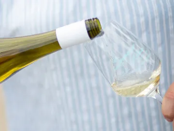 A bottle pours wine into a glass when serving.