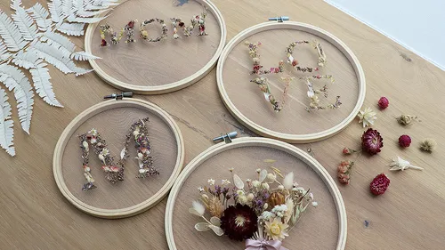 Embroidery hoops with dried flowers spelling words.