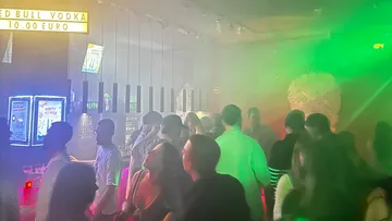 Leute tanzen in einem rauchigen Nachtclub.