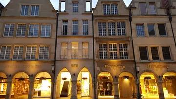 Historic buildings with illuminated arches at dusk.