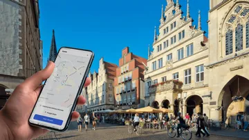 Hand holding phone in European city square.