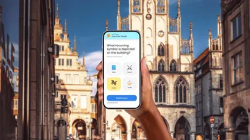 Hand holding phone with quiz in city.