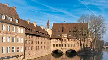 Historisches Gebäude über Fluss mit blauem Himmel.