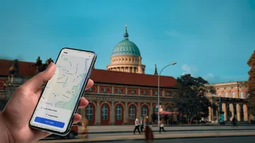 Hand hält Handy mit Karte auf Straße.