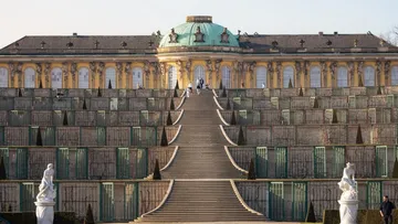 Staatliches Gebäude mit Terrassengarten und Treppen.