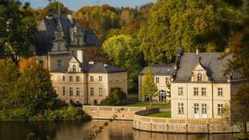 Herrenhaus am See, von Bäumen umgeben.