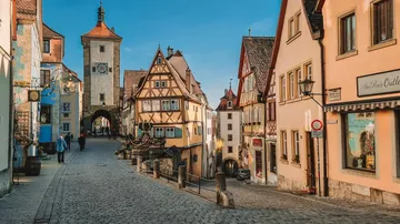 Medieval street with half-timbered houses, people walking.