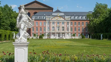 Statue im Vordergrund, Palast im Hintergrund Garten.