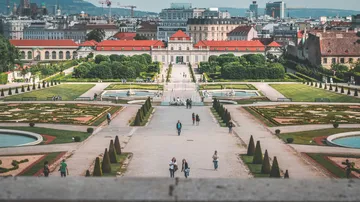 People walking in palace gardens, cityscape background.