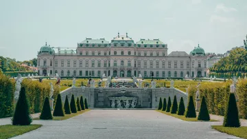 Historischer Palast mit gepflegten Gärten und Skulpturen.