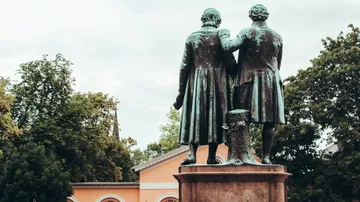 Zwei Statuen stehen zusammen, umgeben von Bäumen.