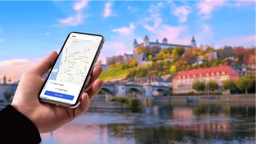 Hand hält Handy mit Karten-App nahe Schloss.