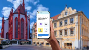 Hand hält Telefon vor einer Kirche.