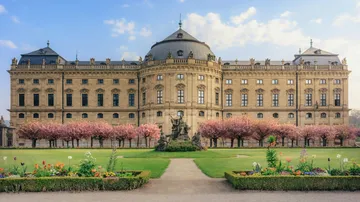 Großes historisches Gebäude mit Gärten und Bäumen.