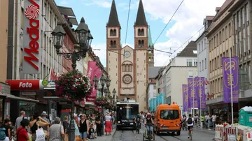 Straße mit Straßenbahn, Kirche und geschäftigen Fußgängern.