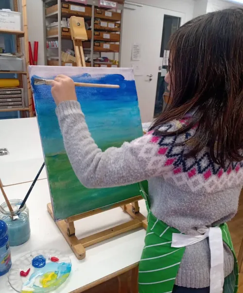 Mädchen malt auf Leinwand im Kunstklassenzimmer.