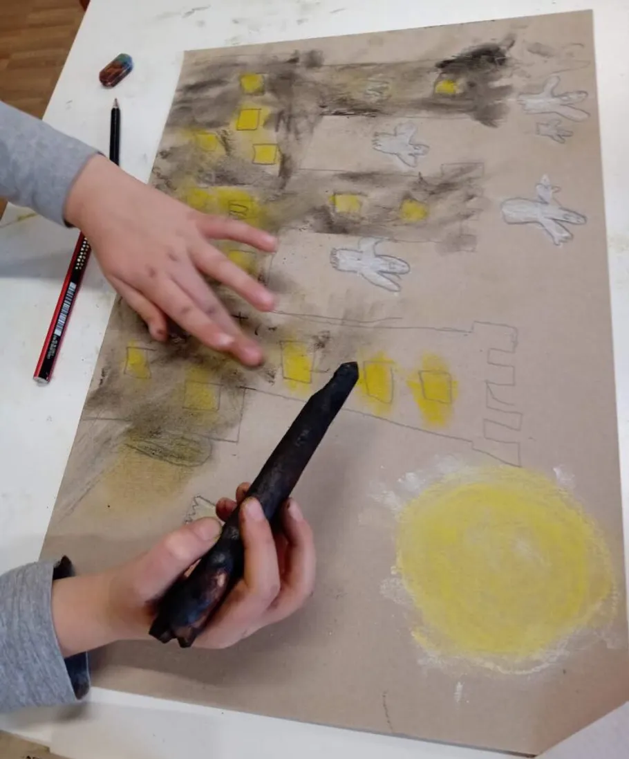 Child draws with pastel on paper.