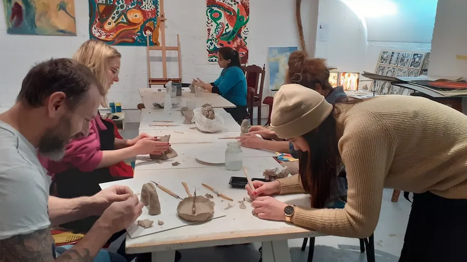 People sculpting clay at art workshop.