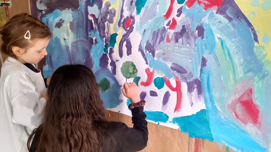 Two children painting a colorful mural together.