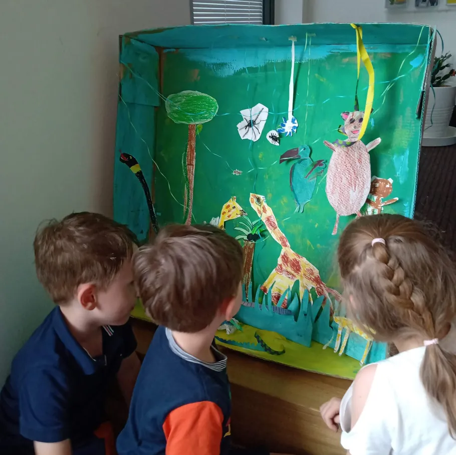 Kinder beobachten ein buntes Dschungel-Diorama.