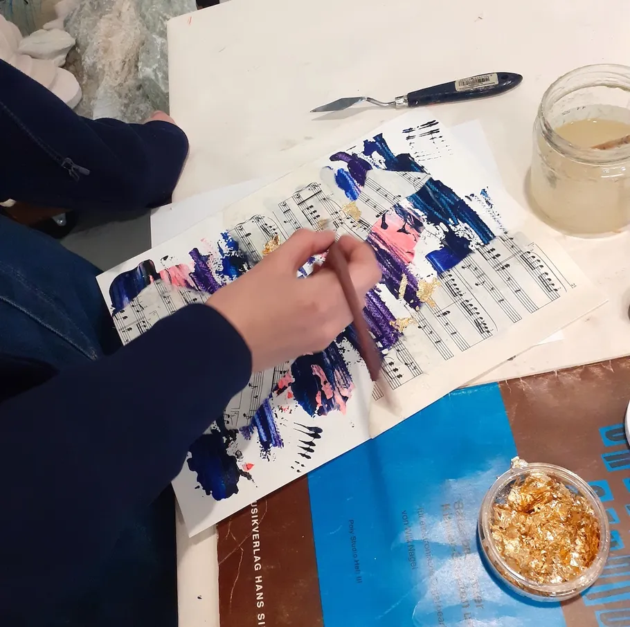 Person malt abstrakte Kunst auf Notenblatt.