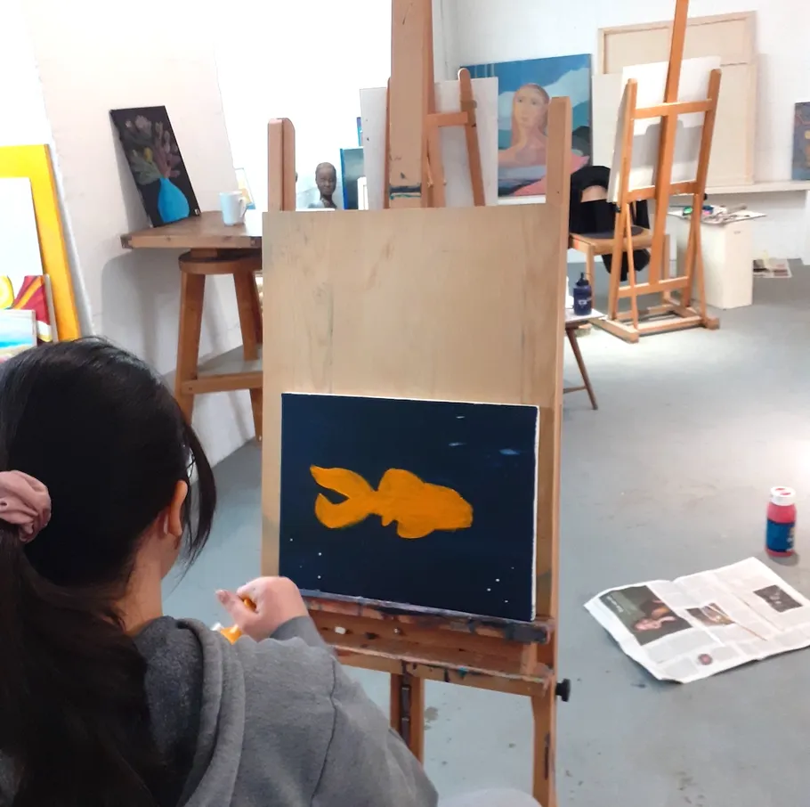 Person malt Goldfisch in einem Atelier.