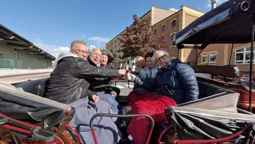 Gruppe stößt in einer Kutschfahrt an.