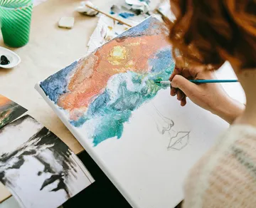 Person painting abstract art on canvas.