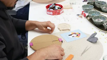 Person crafting with string and tools on table.