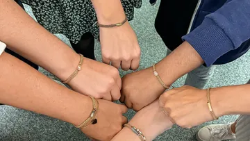 Six arms displaying matching bracelets in a circle.